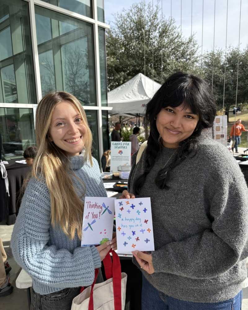 An ambassador holding two handmade cards at a card-making event