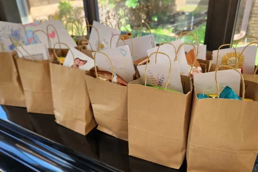 A row of brown paper bags filled with handmade cards, ready to be mailed